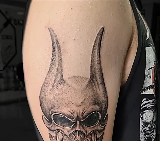 Calavera con cuernos en realismo negro y gris, en el brazo